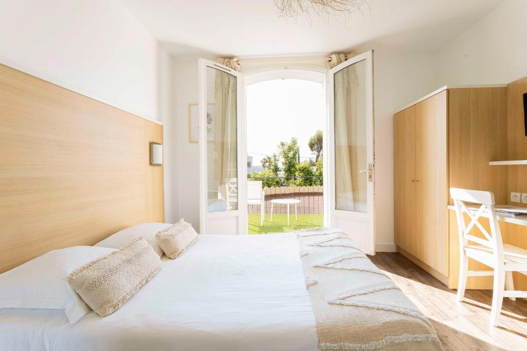 a bedroom with a large bed and a large window at Le Relais d'Agay in Agay - Saint Raphael