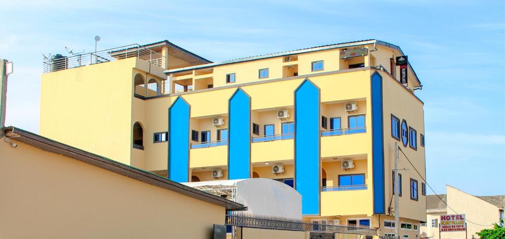 een geel en blauw gebouw met blauwe zuilen bij Glory Palace Hotel in Cotonou