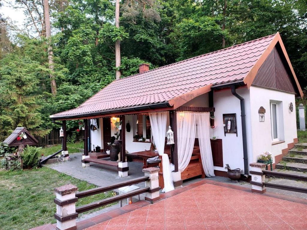 Domek nad Poranną Rosą في Garbatka-Letnisko: منزل أبيض صغير مع شرفة وسياج