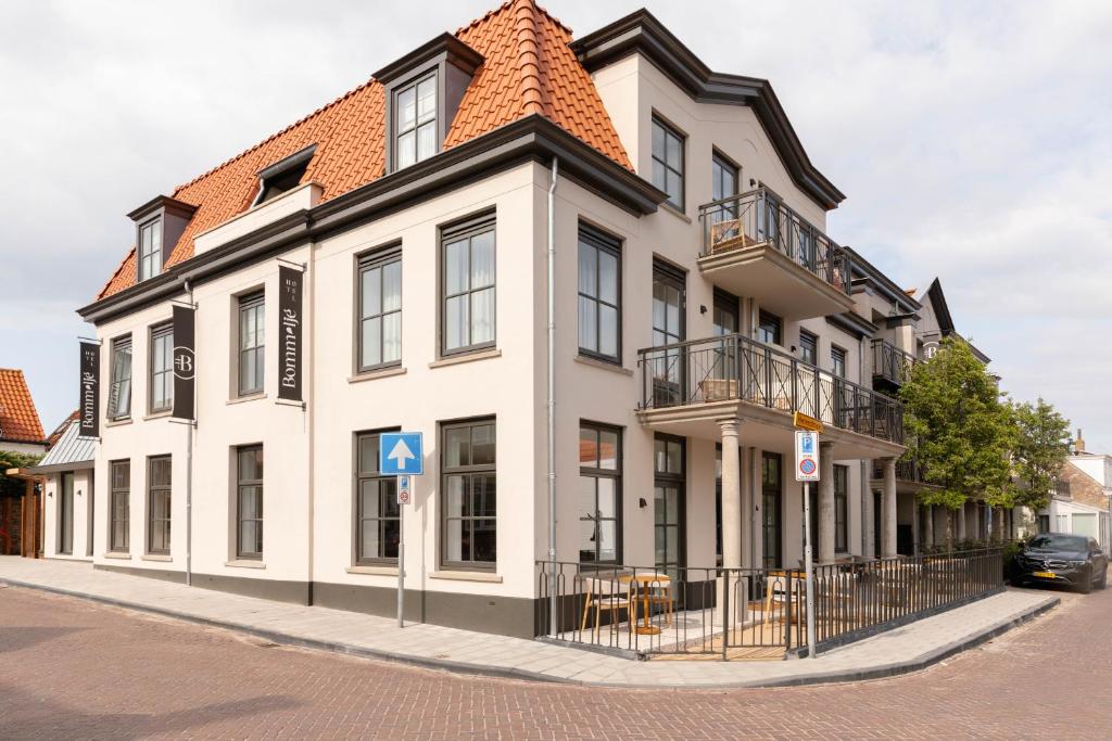 een groot wit gebouw met een tegeldak bij Hotel Bommelje in Domburg