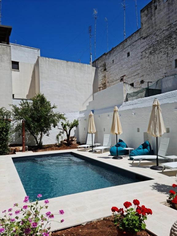 a swimming pool with two umbrellas and flowers at Palazzo Rodio in Ostuni