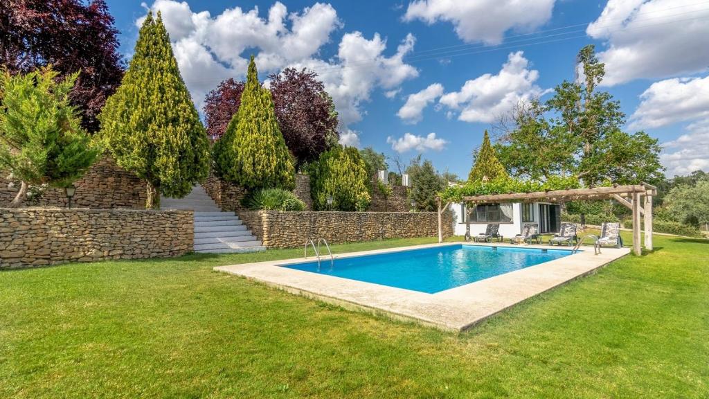 een zwembad in een tuin met een stenen muur bij Casa Los Morales Ronda by Ruralidays in Ronda