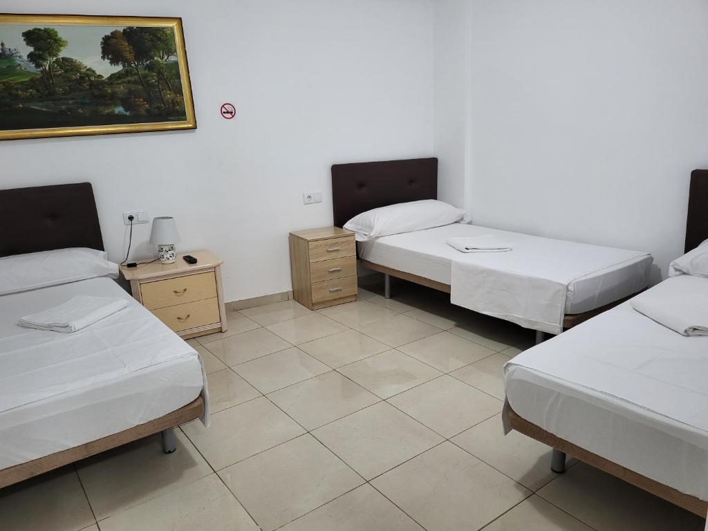 een kamer met drie bedden en een schilderij aan de muur bij pension mexico in Alicante