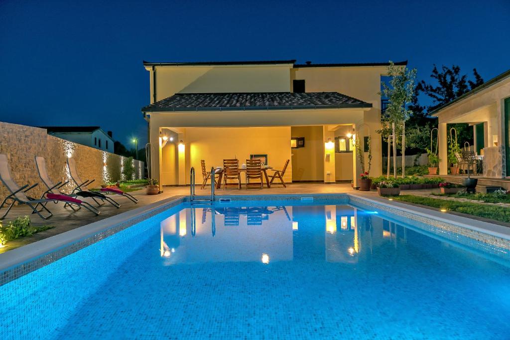 uma piscina em frente a uma casa à noite em Villa Cotabela em Omiš