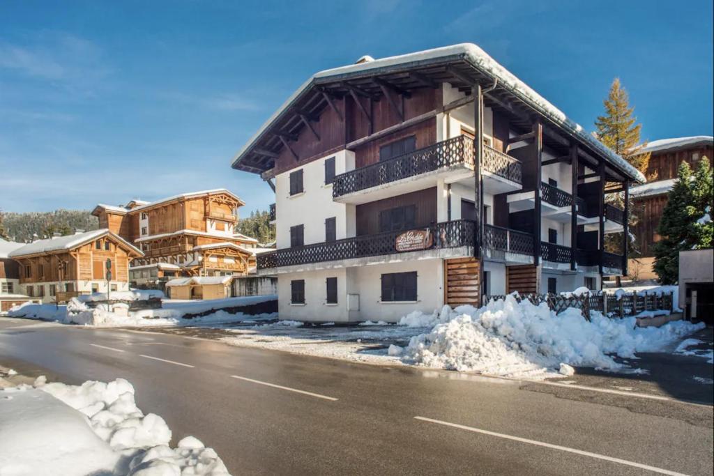 a building on a street with snow on the ground at Résidences Delavay La Cordée in Les Gets