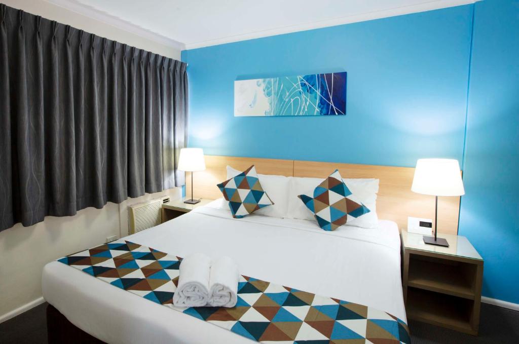 1 dormitorio con 1 cama blanca grande y paredes azules en Metro Apartments on King, en Sídney