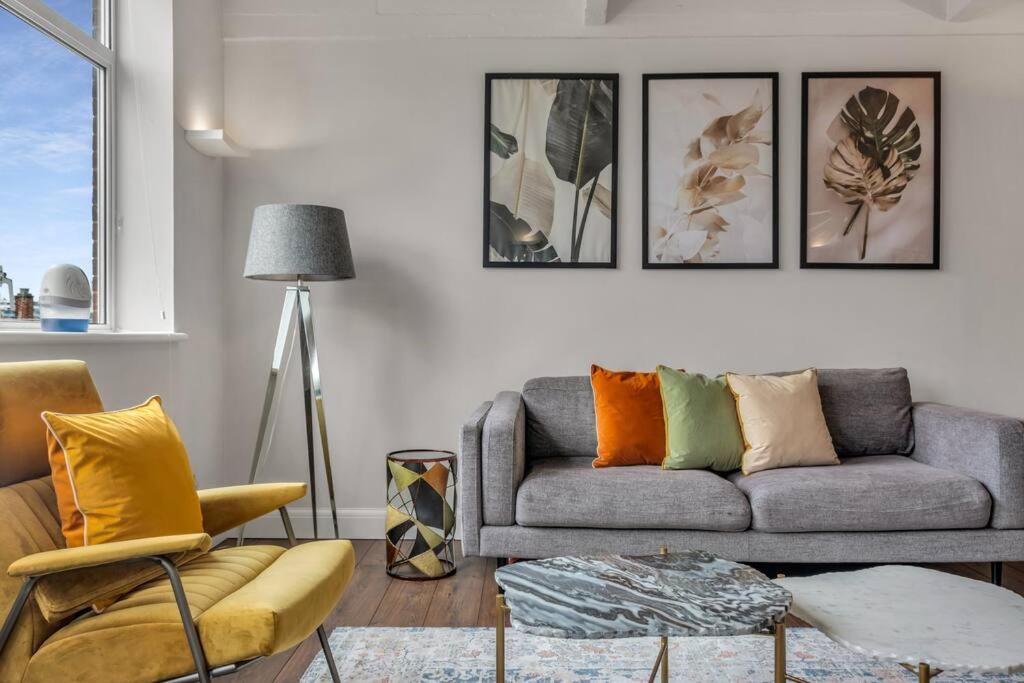 a living room with a gray couch and four pictures on the wall at 3 bed apartment near Old Street and City of London in London