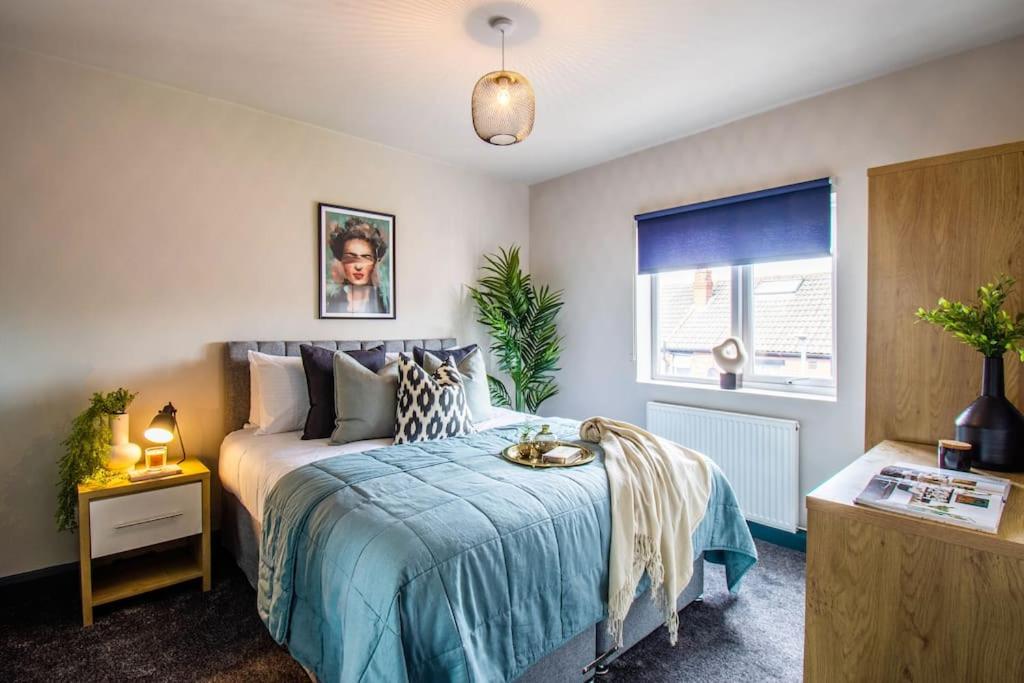 a bedroom with a bed with a blue blanket and a window at Cobden House - 5 Bed, 5 En-suite in Farnley