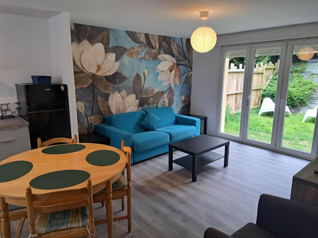 salon ze stołem i niebieską kanapą w obiekcie Appartements Lannion proche centre, Côtes de Granit Rose w mieście Lannion