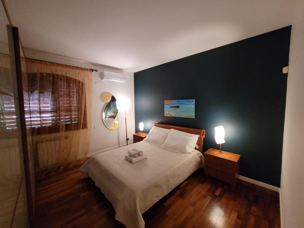 ein Schlafzimmer mit einem Bett und zwei Nachttischen mit Lampen in der Unterkunft VERDESOLE HOUSE in Aci SantʼAntonio