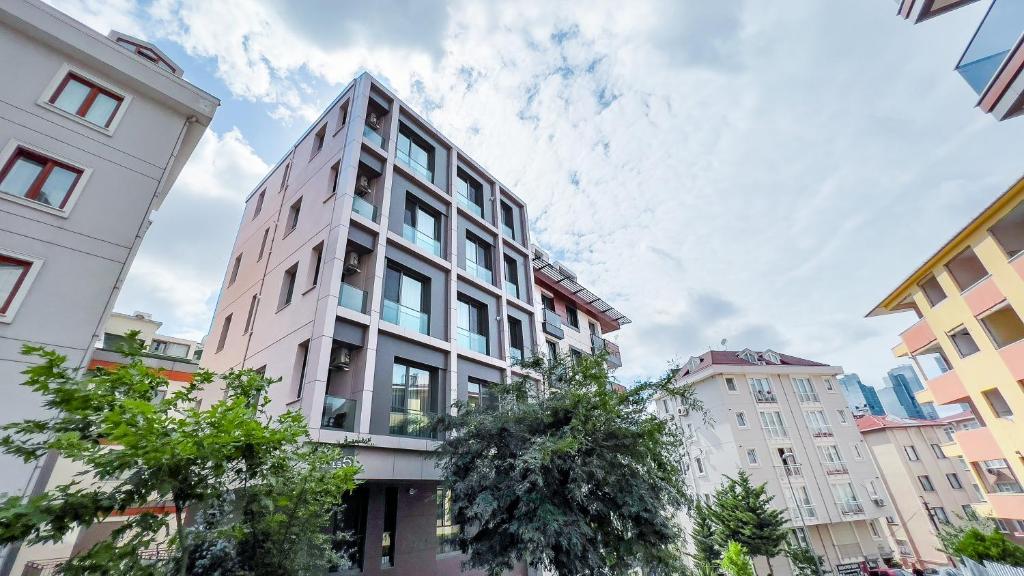 Homie Suites - Newly-constructed Apartment Complex in Beşiktaş في إسطنبول: مبنى أبيض طويل وبه أشجار في المدينة