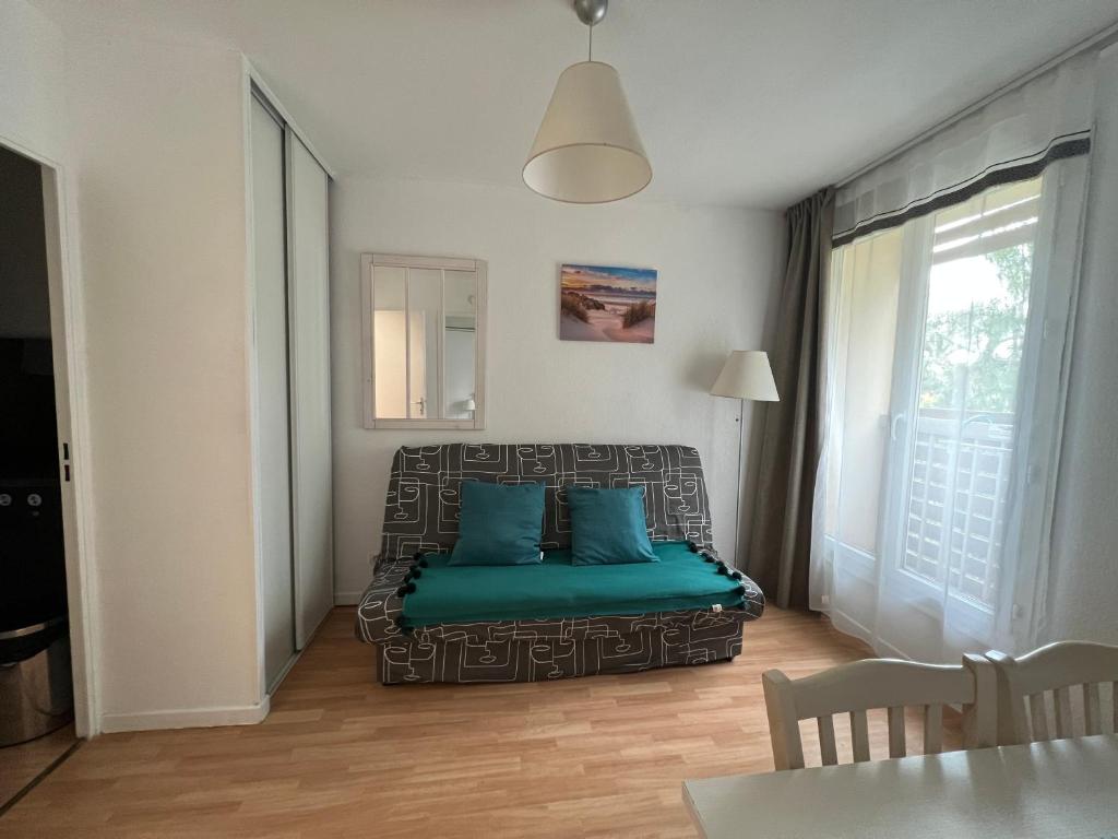 un salon avec un canapé avec des coussins bleus dans l'établissement Joli T2 Climatisé proche plage dans résidence Vacance, à La Londe-les-Maures