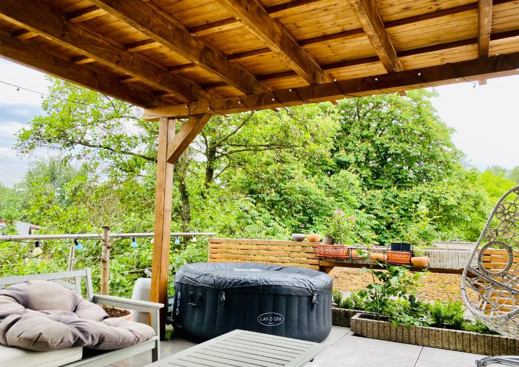 a patio with a wooden pergola and a trash can at CLAY Apartment Bôrik vírivka len v letnom období in Žilina