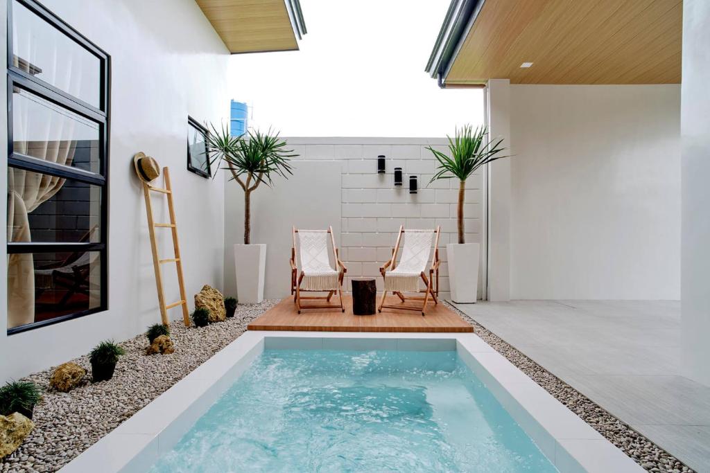 two chairs and a swimming pool in a house at Bali-inspired Villa with Dipping Pool by Pallet Homes in Iloilo City