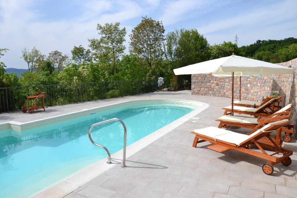 a swimming pool with two chairs and an umbrella at Agriturismo Gradec in Aurisina
