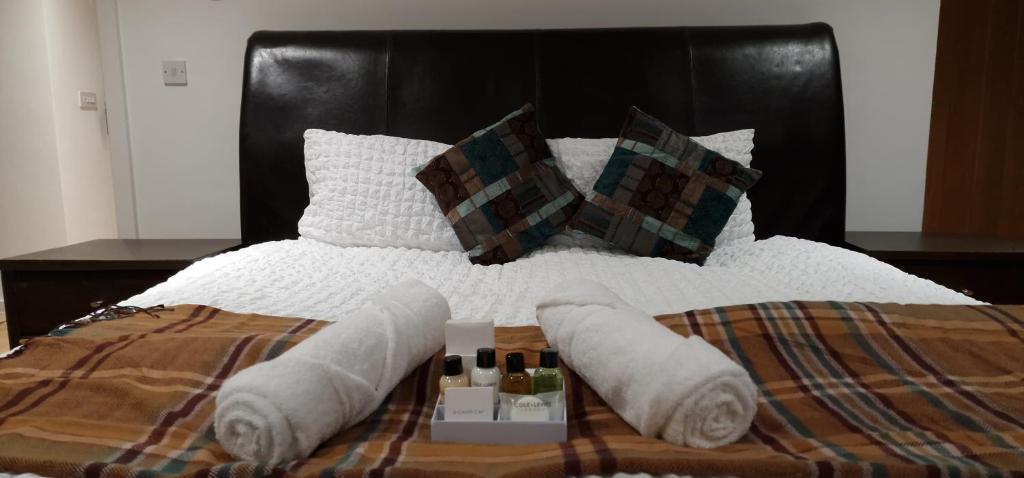 a bed with white sheets and pillows with towels on it at Luxury-Immaculate-Cosy 2-Bed House in Plymouth in Plymouth