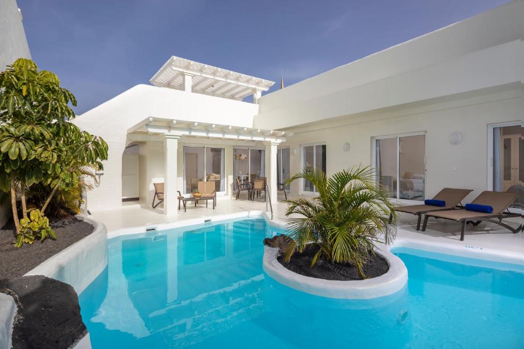 een villa met een zwembad en een patio bij Bahiazul Resort Fuerteventura in Corralejo
