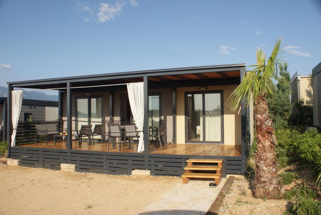 una casa en la playa con una terraza con sillas en Sweet Dreams mobile home, Terra Park SpiritoS en Kolan