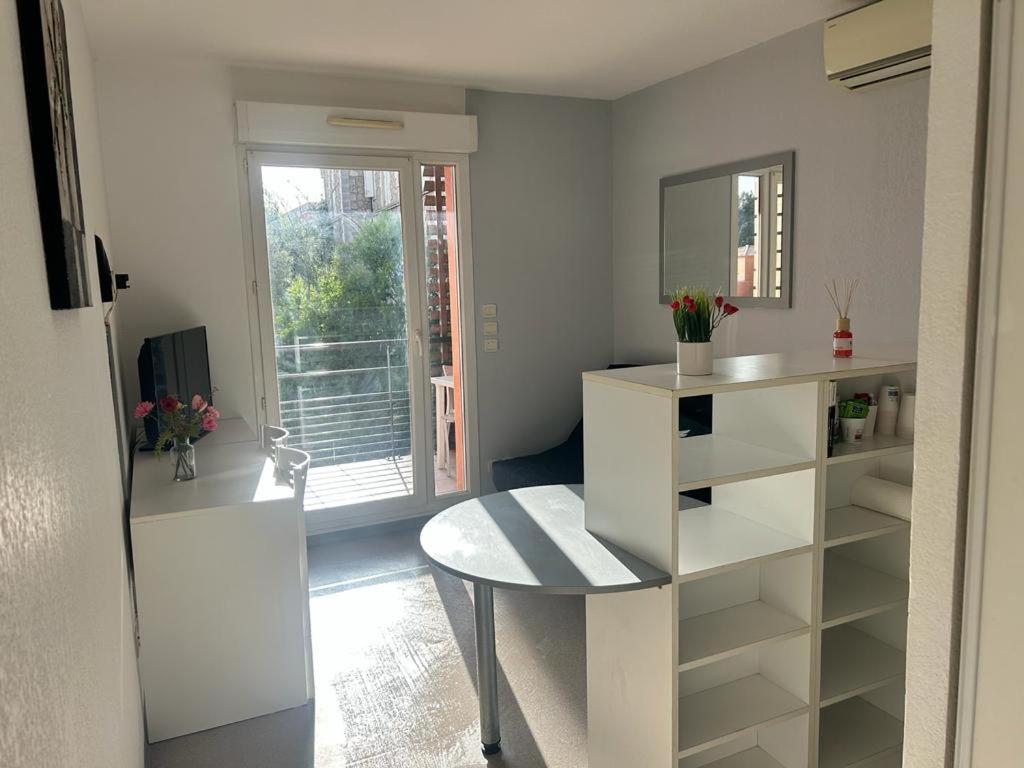 een witte keuken met een tafel en een spiegel bij Studio residence de tourisme le Fonserane in Béziers