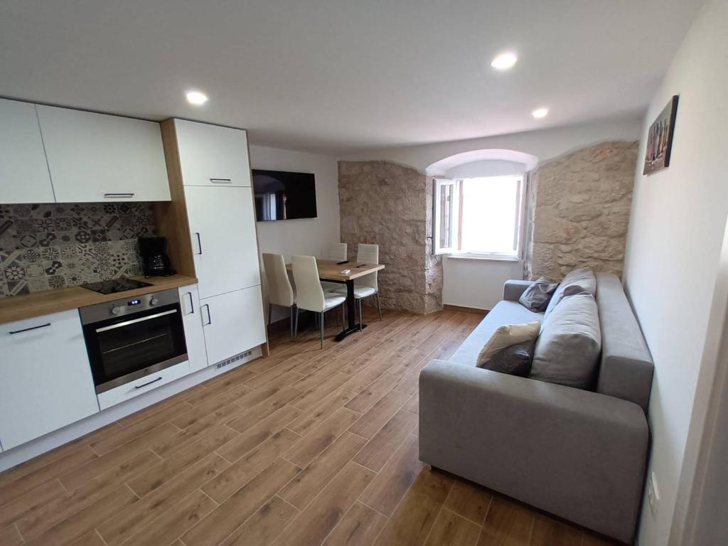 ein Wohnzimmer mit Couch und Küche in der Unterkunft Apartment Triton in the old Part of Baska in Baška