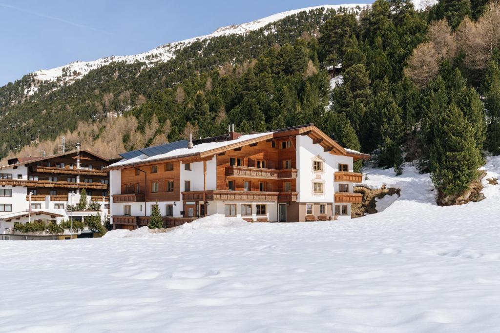 un grande edificio nella neve di fronte a una montagna di Hotel Macun a Vent