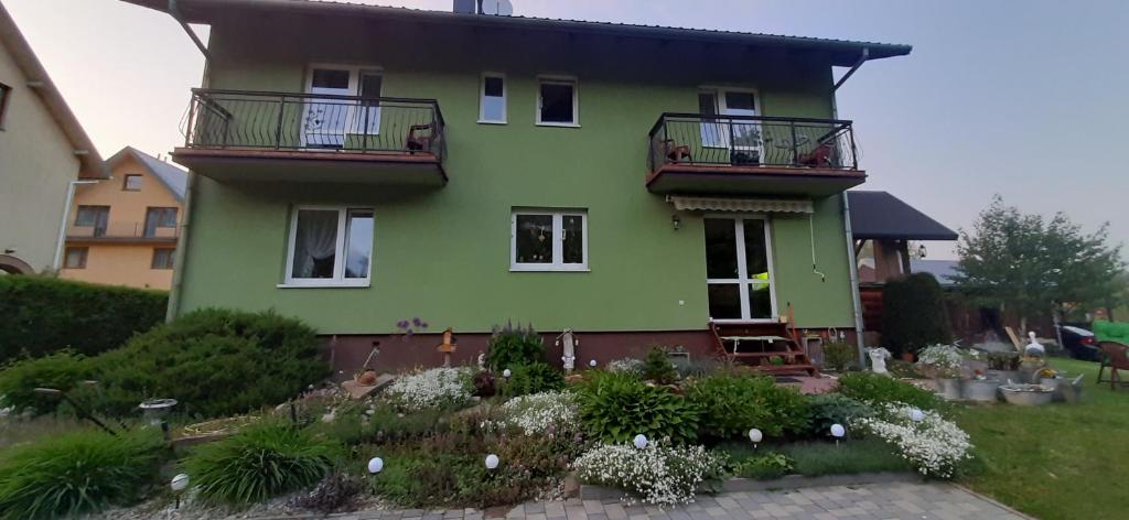 une maison verte avec 2 balcons et un jardin dans l'établissement Zielony Domek, à Tylicz