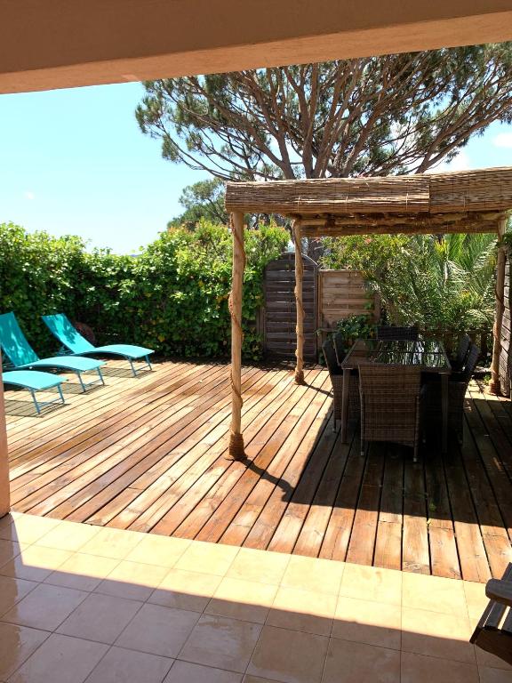 une terrasse en bois avec des chaises et une table dans l'établissement Maisonnette Antelissa à 3 minutes en voiture des plages et du centre ville, à Saint-Tropez