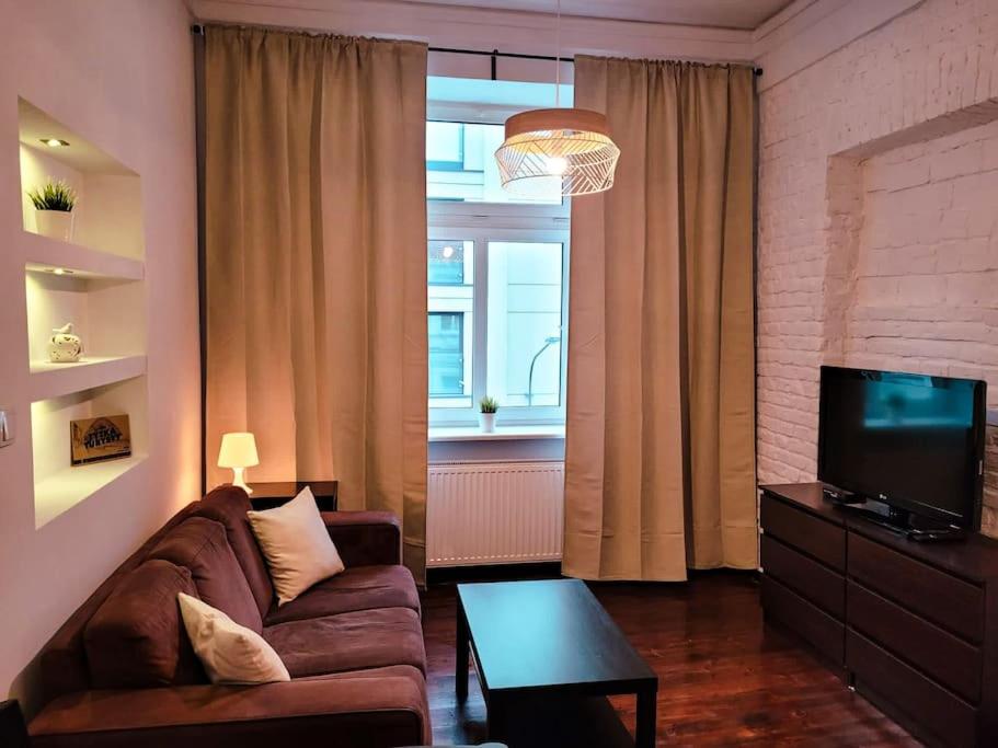 a living room with a couch and a tv at Rent-Apart City Center - apartament z 1 sypialnią in Łódź
