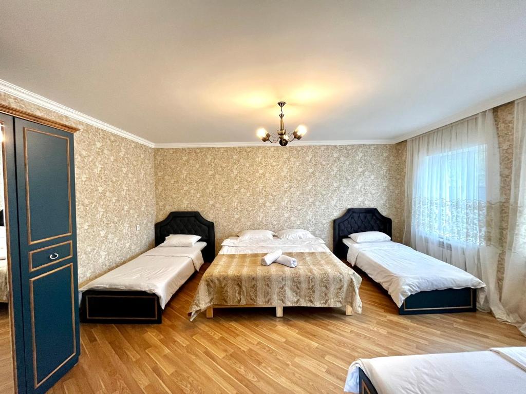 a room with three beds and a table in it at Secret Garden Guest House in Gabala