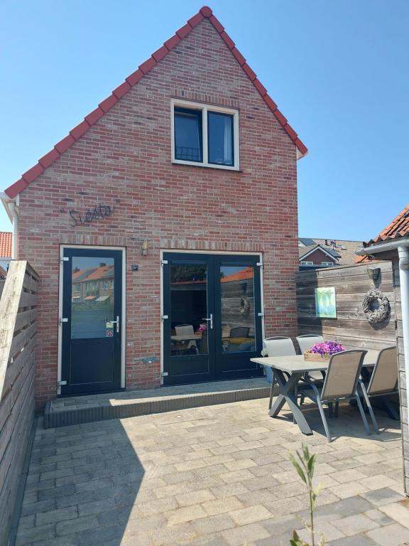 a brick building with a patio with a table and chairs at Siësta in Westkapelle