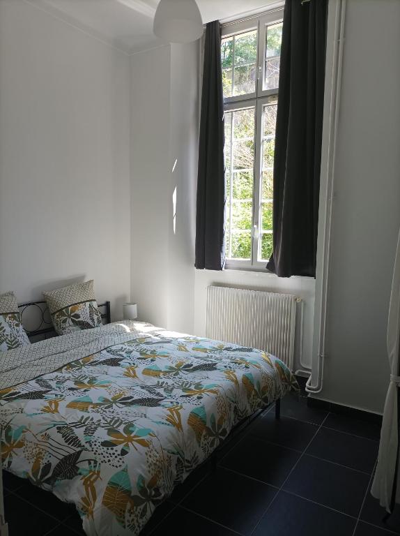 a bedroom with a bed with a colorful comforter and a window at O&#39;Couvent - Appartement 62 m2 - 2 chambres - A513 in Salins-les-Bains