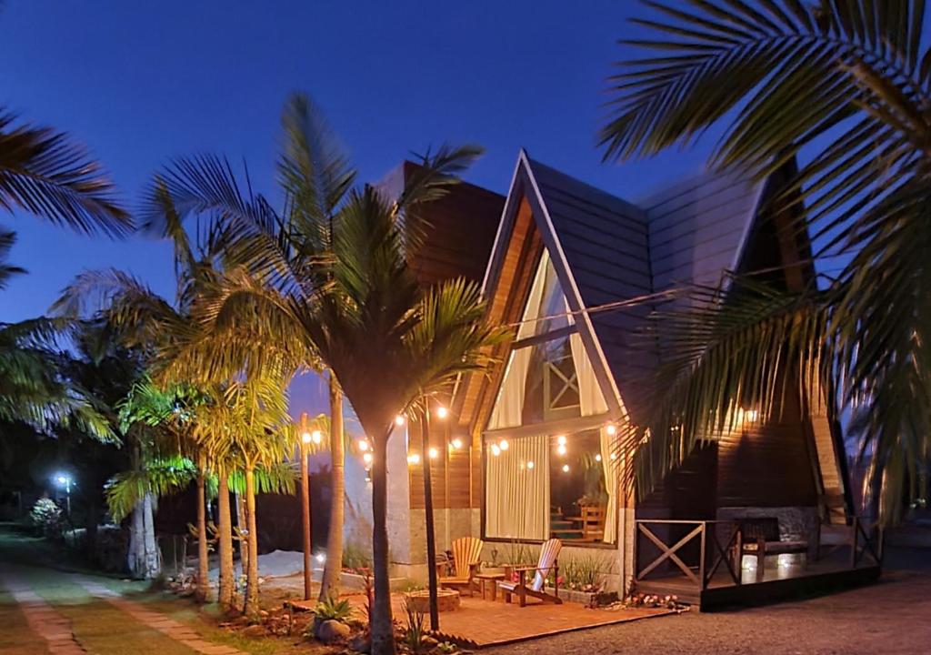 a building with palm trees in front of it at AriMara Chalés & Ecoturismo in Praia Grande