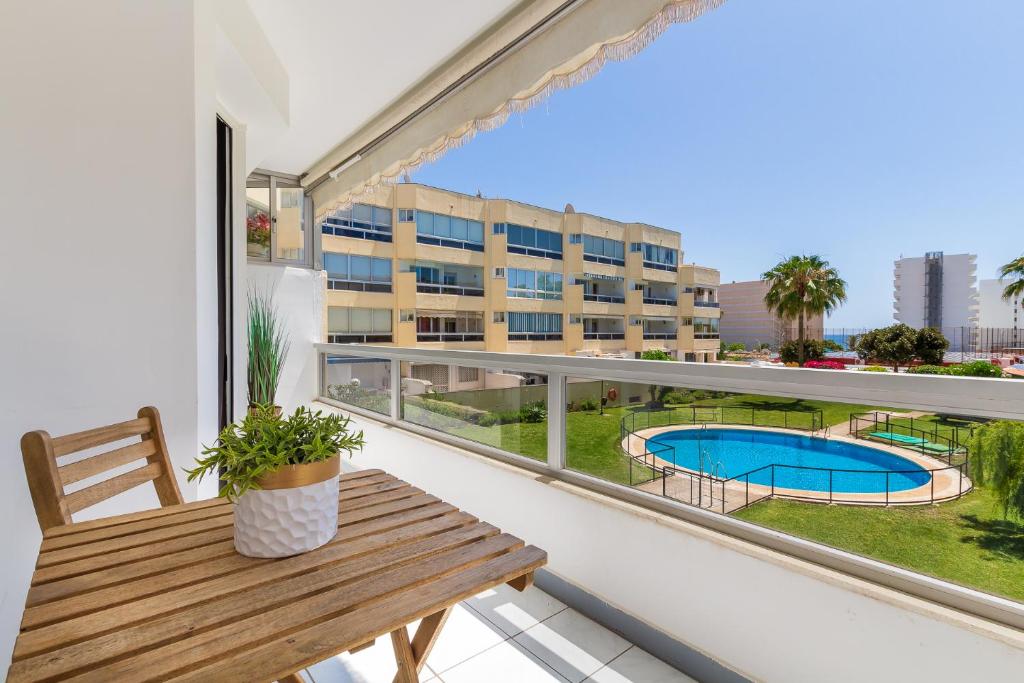 a balcony with a wooden bench and a swimming pool at Vistamarina B201 By IVI Real Estate in Torremolinos