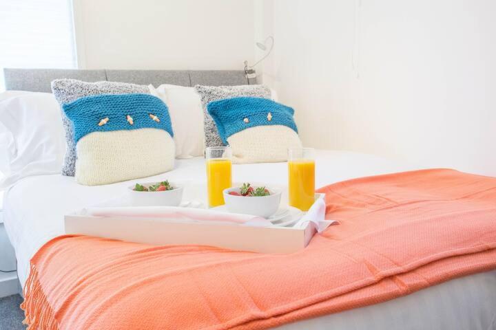 taca z jedzeniem na łóżku z dwoma kieliszkami soku pomarańczowego w obiekcie Snug with Views of the Chilterns 