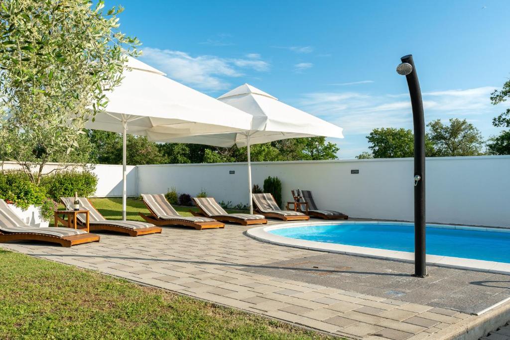 um pátio com cadeiras, um guarda-sol e uma piscina em House Leonardo em Galovac