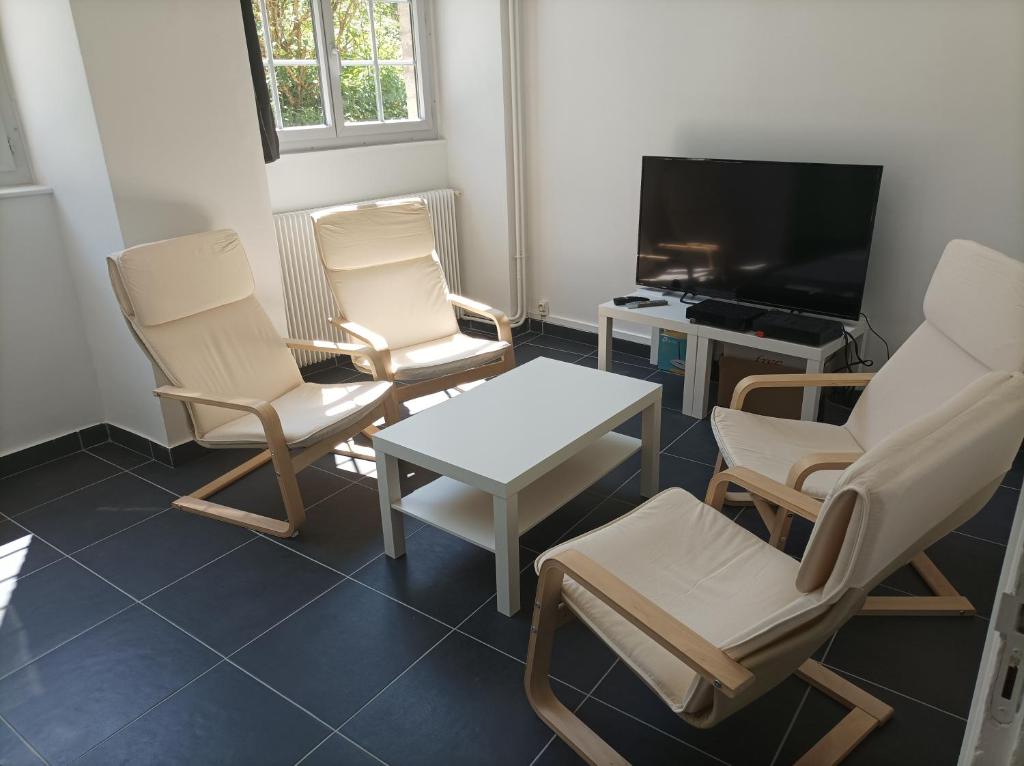 a living room with two chairs and a table and a television at O'Couvent - Appartement 79 m2 - 2 chambres - A512 in Salins-les-Bains