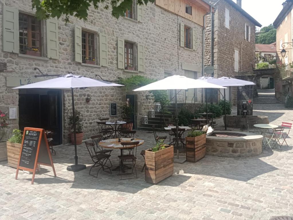 a patio with tables and umbrellas in front of a building at LAne Têtu in Désaignes