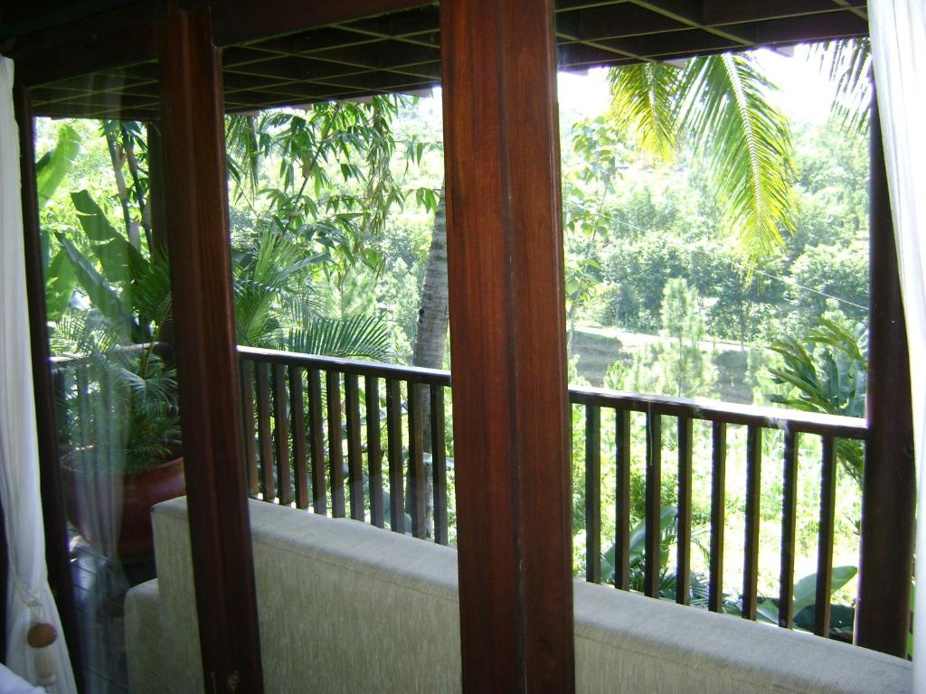 a balcony with a view of a palm tree at Swaloh Resort & Spa in Kalangbret