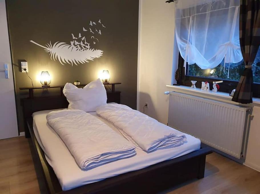 een bed met witte lakens en kussens in een kamer bij 1 Raum-Ferienwohnung am Rosenberg in Goslar