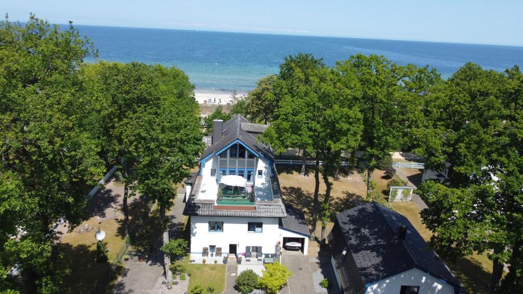 an aerial view of a white house with trees and the beach at Strandvilla Miramare in Boltenhagen