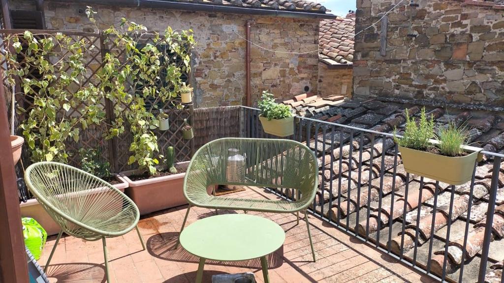 twee stoelen en een tafel op een patio met planten bij La tua casa nel Chianti in San Donato in Poggio