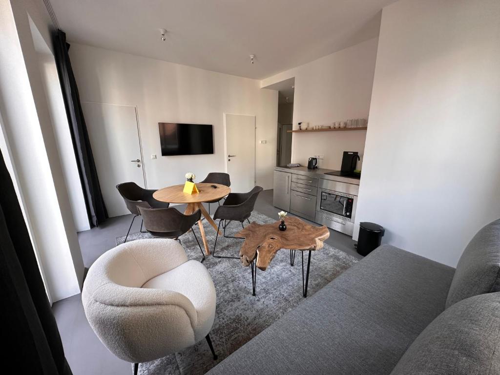 uma sala de estar com um sofá, uma mesa e cadeiras em Rilke Apartments em Linz