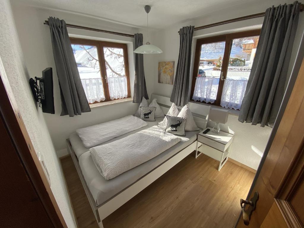 a small bedroom with a bed and two windows at Apartment Hermine in Jochberg
