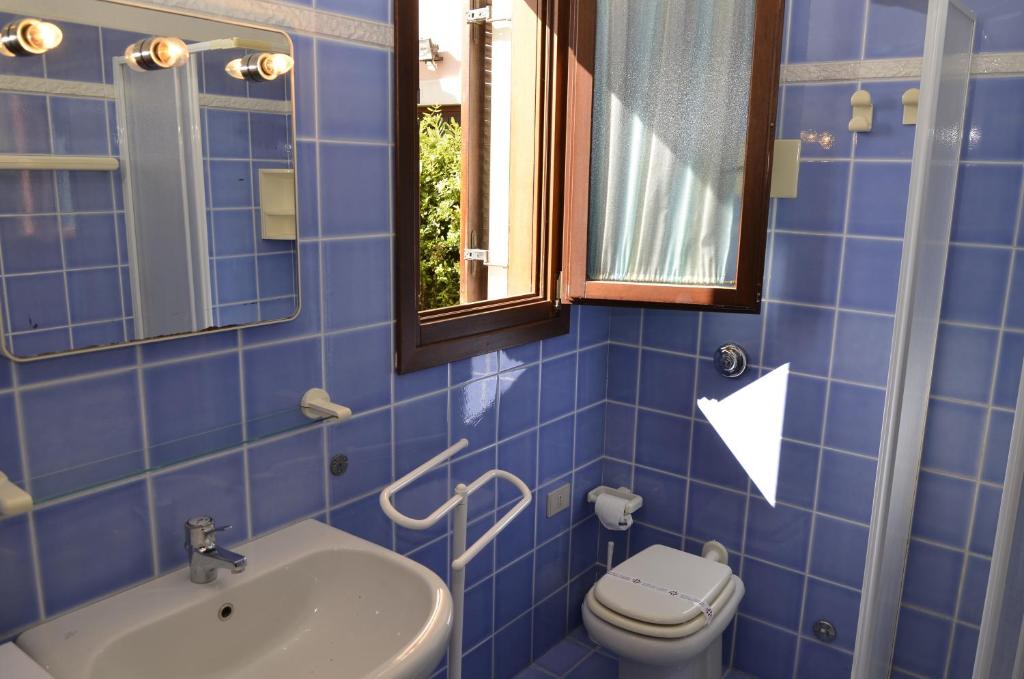 niebieska kafelkowa łazienka z toaletą i umywalką w obiekcie Le Villette al Centro w mieście San Teodoro
