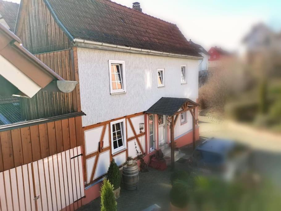 ein großes weißes Haus mit einer Veranda neben einem Zaun in der Unterkunft Ferienhaushaus Marie in Wildeck in Bosserode