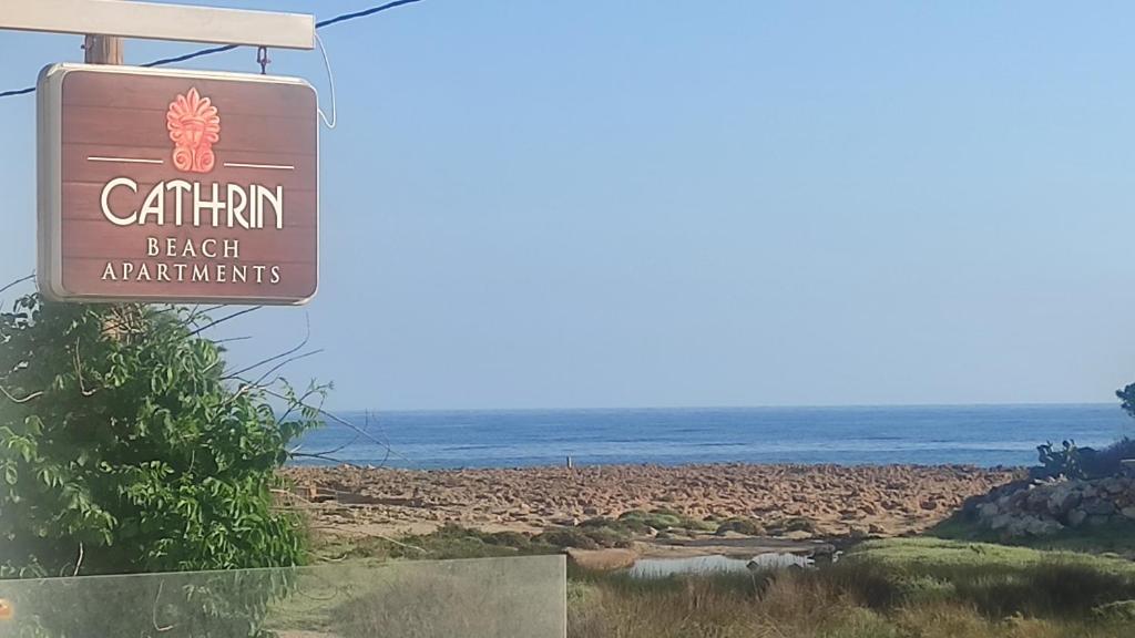 un cartello per la spiaggia con l'oceano sullo sfondo di Cathrin Beach Apartments a Stavros