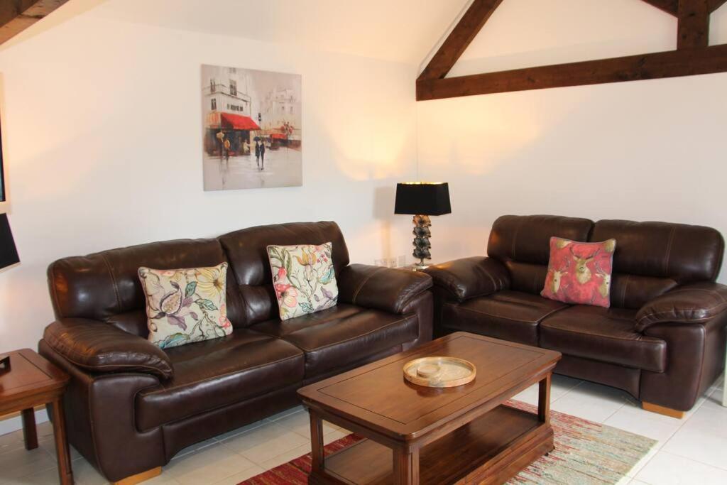uma sala de estar com um sofá de couro e uma mesa em Peaceful and tranquil 2 bedroom Deer Cottage em Chippenham