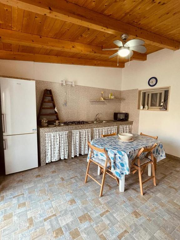 eine Küche mit einem Tisch und einem weißen Kühlschrank in der Unterkunft Appartamento - Rosamarina in Torre Colimena