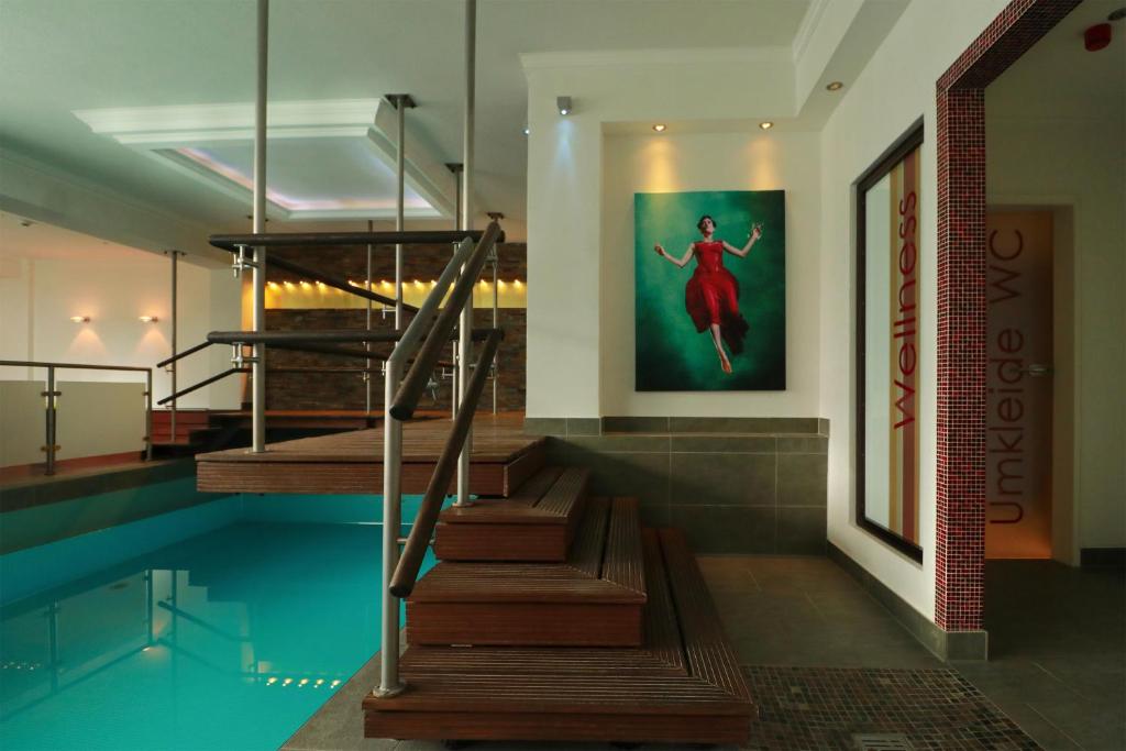 a swimming pool with stairs and a painting on the wall at Hotel Haverkamp in Bremerhaven