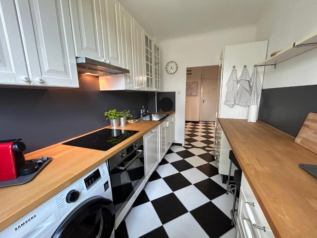 a kitchen with white cabinets and a black and white checkered floor at Apartment Wien West in Vienna